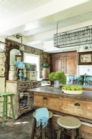 Rose patterned wallpaper, unpretentious storage cabinetry, an unusual rectangular chandelier, and a repurposed shop workbench island appear to have come together following centuries of decorating.
