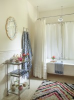 Striped towels and zigzag rainbow rug add zip to an all-white bath.  In a neutral space like this, itâ€™s easy to dramatically change out the look of the room simply by playing with the accessories. 
