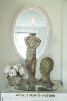 A cherub statue, fabric roses and a glittering head form set a romantic vignette on an old metal cabinet in the bedroom.