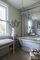 An ample antique tub, a linen-clad bench and an oversize mirror set the bathroom elegant mood. 