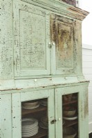 A distressed mint-green hutch houses disbaware and table linens.