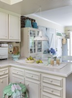 Simplicity is always in style. In this case, an all-white kitchen gets little touches of colorful and rustic touches that keeps the mood light and homey.