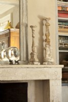 Old wood candlesticks impart a sculptural interest to the limestone mantle.