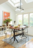 Machinist stools surround a retro drafting table repurposed for casual dining. 