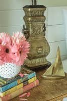 An urn-shaped metal lamp and a tiny brass sailboat grace a bedside table.