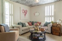 The cloud wallpaper on the ceiling bring a touch of faded  glamour to the living room.