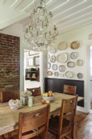 A rustic brick walls and a pine farmhouse table paired with antique schoolhouse chairs.