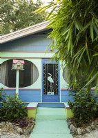 The front porch of the brightly colored cottage features unusual oval screened window openings. 