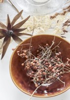 Detail of dried flower arrangement and bowl on rustic dining table