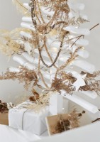 Dried fern leaves on bead decorations on white Christmas tree