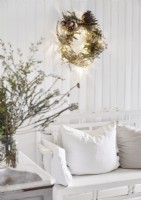 Illuminated Christmas wreath on white wall above sofa