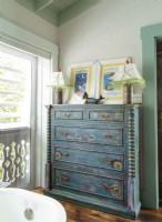 A modern chest of drawers is transformed into a antique with a multi-layers of paint, paisley swirls, and sunburst motifs. 