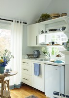 White cabinets and counters complement the classic cottage style and help make the little home feel more spacious.