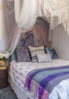 Hung from the ceiling, white mesh fabric and vintage fringed shawls create a canopy in the guest bedroom.