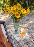 A garden table keeps drinks handy. Iconic symbol of Tuscany,  sunflowers are gathered in a golden bouquet.