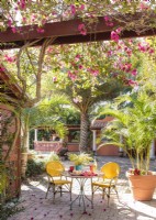 A bistro table tucked under bougainvillea vines and palms evoke an open-air Tuscan courtyard 