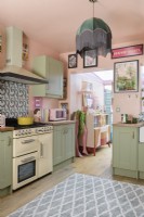 A pale pink and green retro Shaker style kitchen with view through to conservatory 