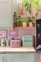 Detail of retro kitchen wooden counter top with a pale green vintage bread bin and retro style pink toaster