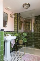 White and sink and shower cubicle in a green tiled and pale pink bathroom 