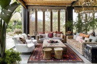 Enclosed veranda with rattan furniture, slip covered armchairs and plants  