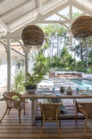 Covered outdoor dining area overlooking swimming pool and garden