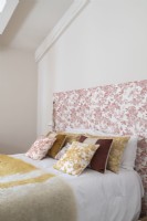 Floral headboard and vintage fabric cushions on bed