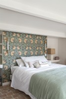 Wallpapered feature wall behind bed in country bedroom