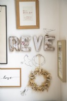 Detail of distressed wooden lettering and framed art on wall