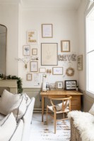 Display of framed artwork on wall above desk and chair