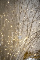 Detail of bare branches covered in fairy lights and ceramic stars