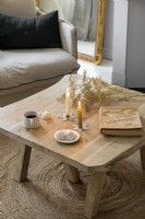 Candles and dried flowers on small rustic wooden coffee table