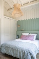 Pastel blue painted wooden walls and bedding in country bedroom