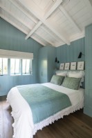 Blue painted wooden walls in country bedroom