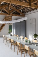 Long dining table and old school chairs in barn at Christmas