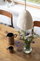 Wildflower arrangement in vase on wooden dining table