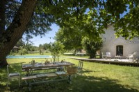 Rustic outdoor dining area under tree on lawn of country garden