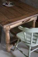 Detail of wooden dining table and pale blue painted chair