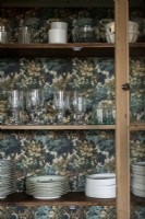 Detail of dining room dresser with patterned wallpaper backing 