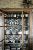 Wooden dresser with wallpaper backing in country dining room