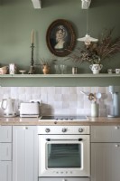 Classic portrait on painted wall above shelf in vintage kitchen