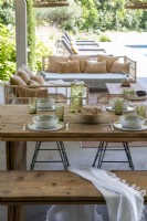 Large wooden outdoor dining table laid for meal 