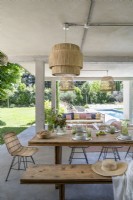 Covered outdoor dining area with view to swimming pool in garden