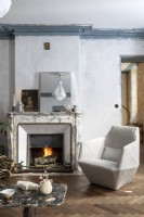 Modern armchair in country living room with lit fire