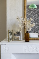 Dried honesty in vase on mantelpiece with vintage photo frame