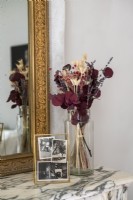 Dried flower arrangement and photographs on marble mantelpiece