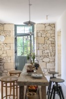 Rustic table in country kitchen-diner with exposed stone walls 