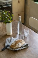 Detail of rustic loaf of bread on wooden kitchen table