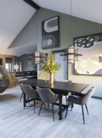 Large artwork on green painted wall of contemporary dining area