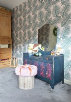 Painted dressing table against wallpapered wall in eclectic bedroom