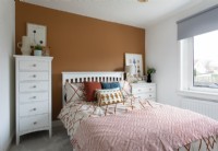 Brown feature wall in modern bedroom with tallboy drawers 